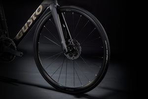 Close-up of a bicycle wheel with 'Custo' branding on a dark background